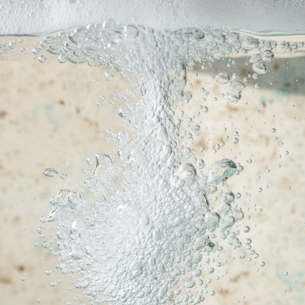 Close view of white bubbles rising through a glass of clear water